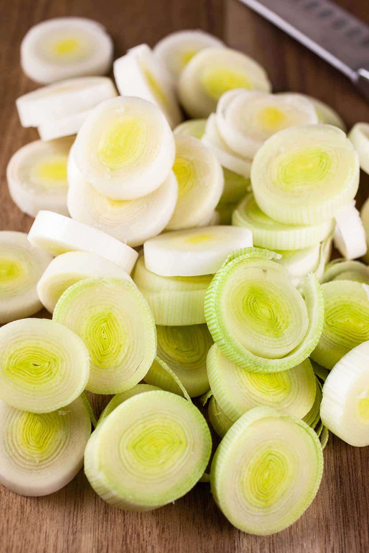 Chopped leeks on wooden cutting board.