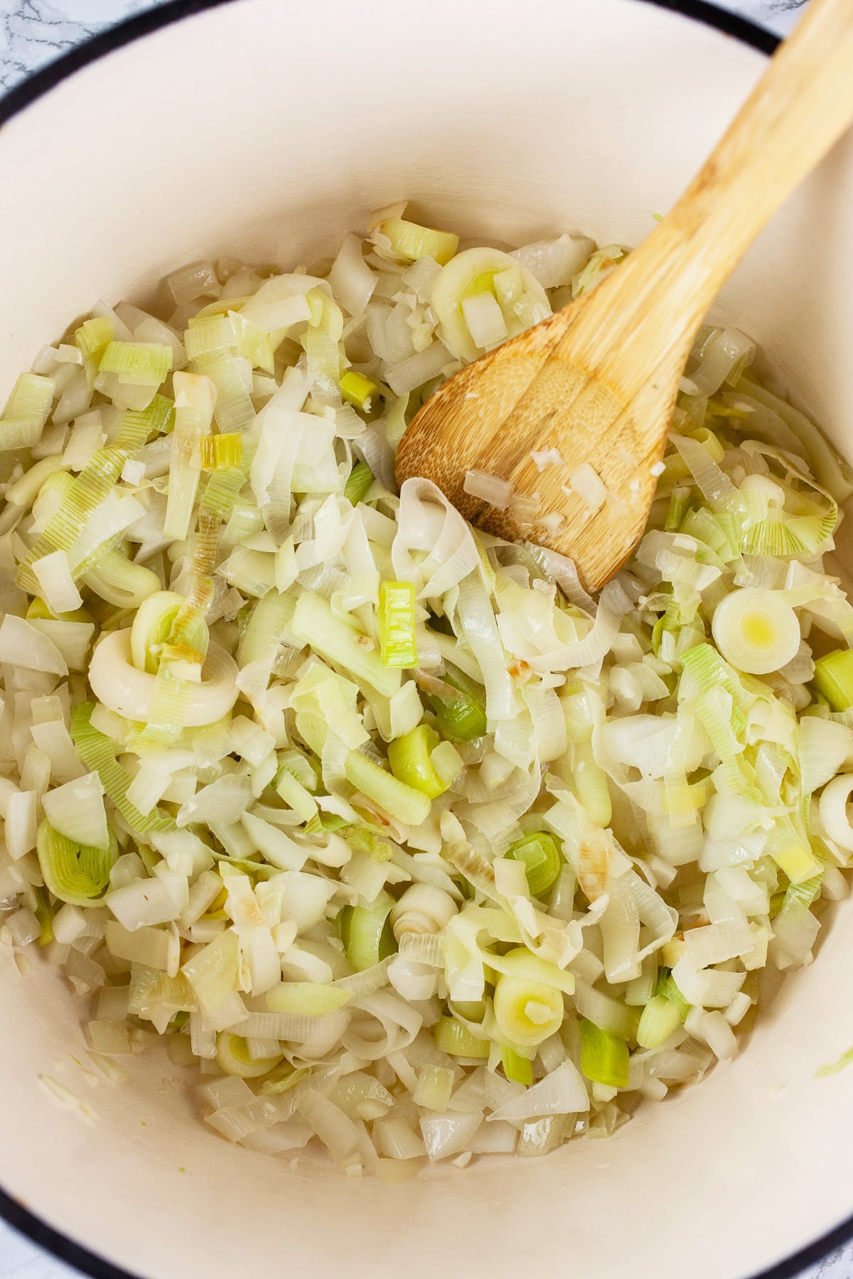 Leeks, garlic, and onions sautéed in Dutch oven with wooden spoon.