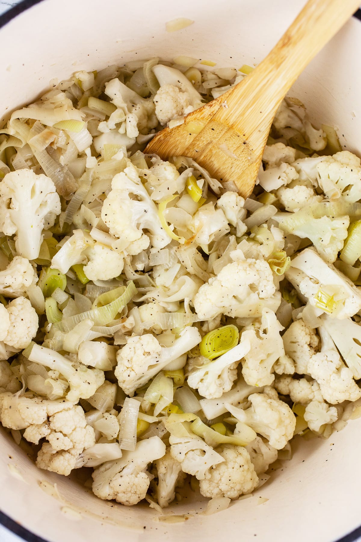 Leeks, garlic, onions, and cauliflower sautéed in Dutch oven with wooden spoon.