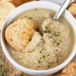 Potato leek cauliflower soup with crostini in small white bowl.