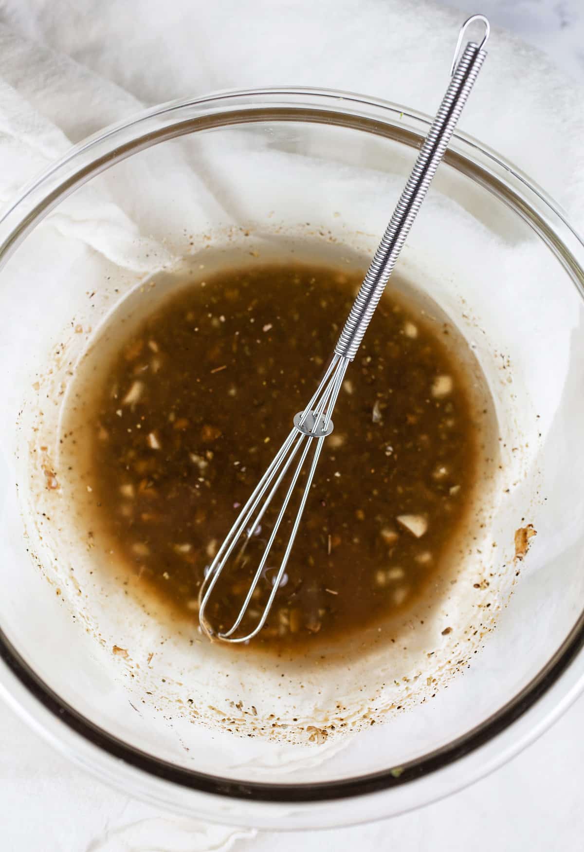 Balsamic dressing in small glass bowl with whisk.