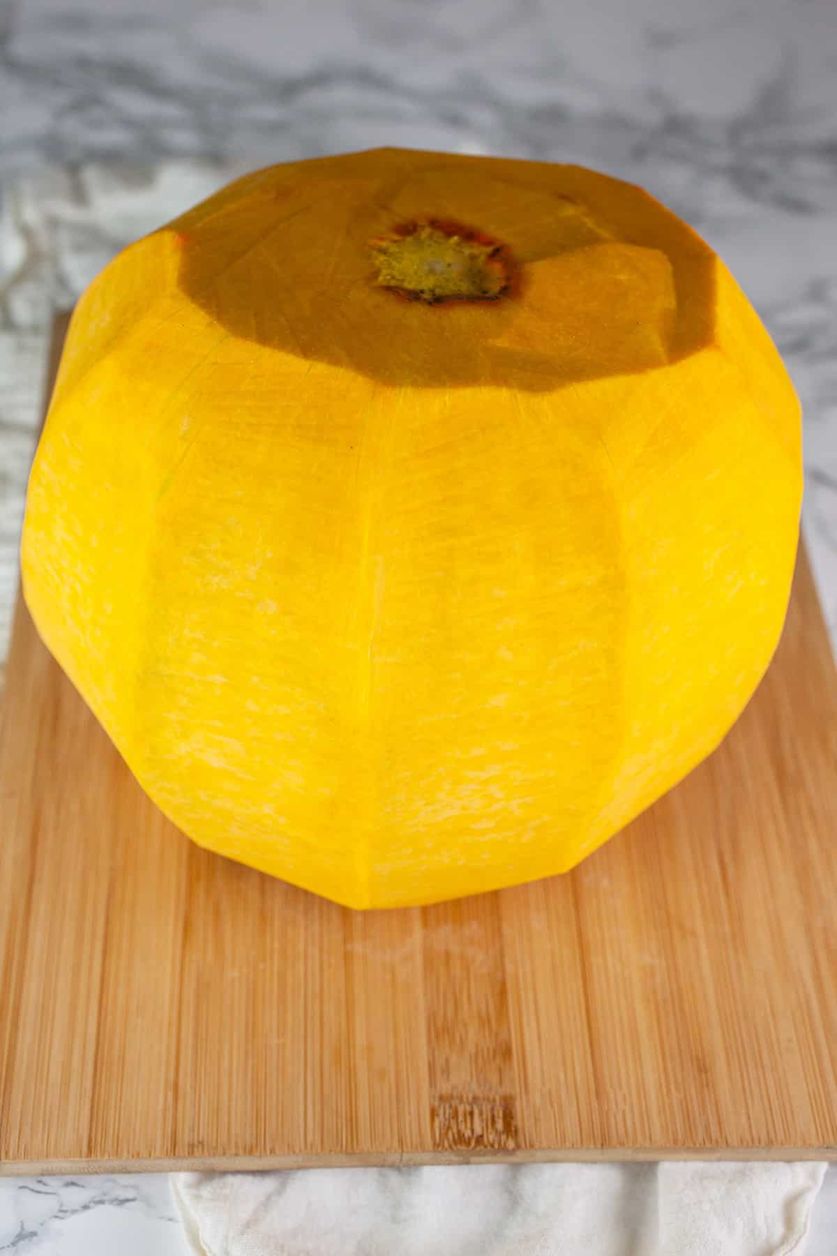 Peeled pumpkin on wooden cutting board.