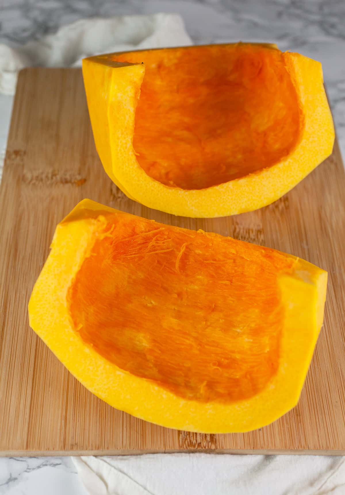Peeled pumpkin half cut into halves.