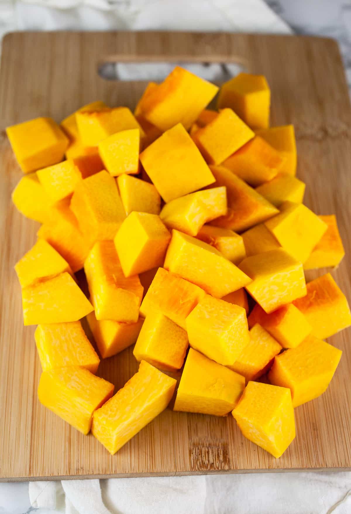 Pumpkin chunks on wooden cutting board.