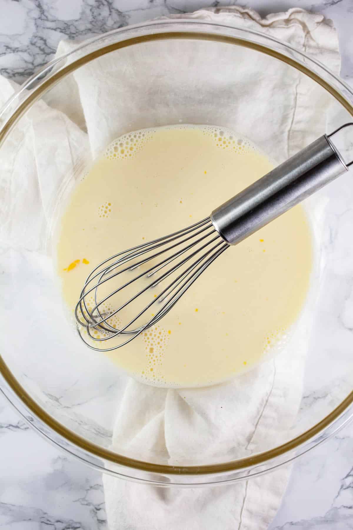 Milk and eggs whisked in glass bowl.