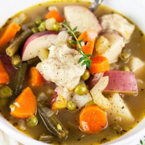 Vegetable stew with dumplings in white bowl.