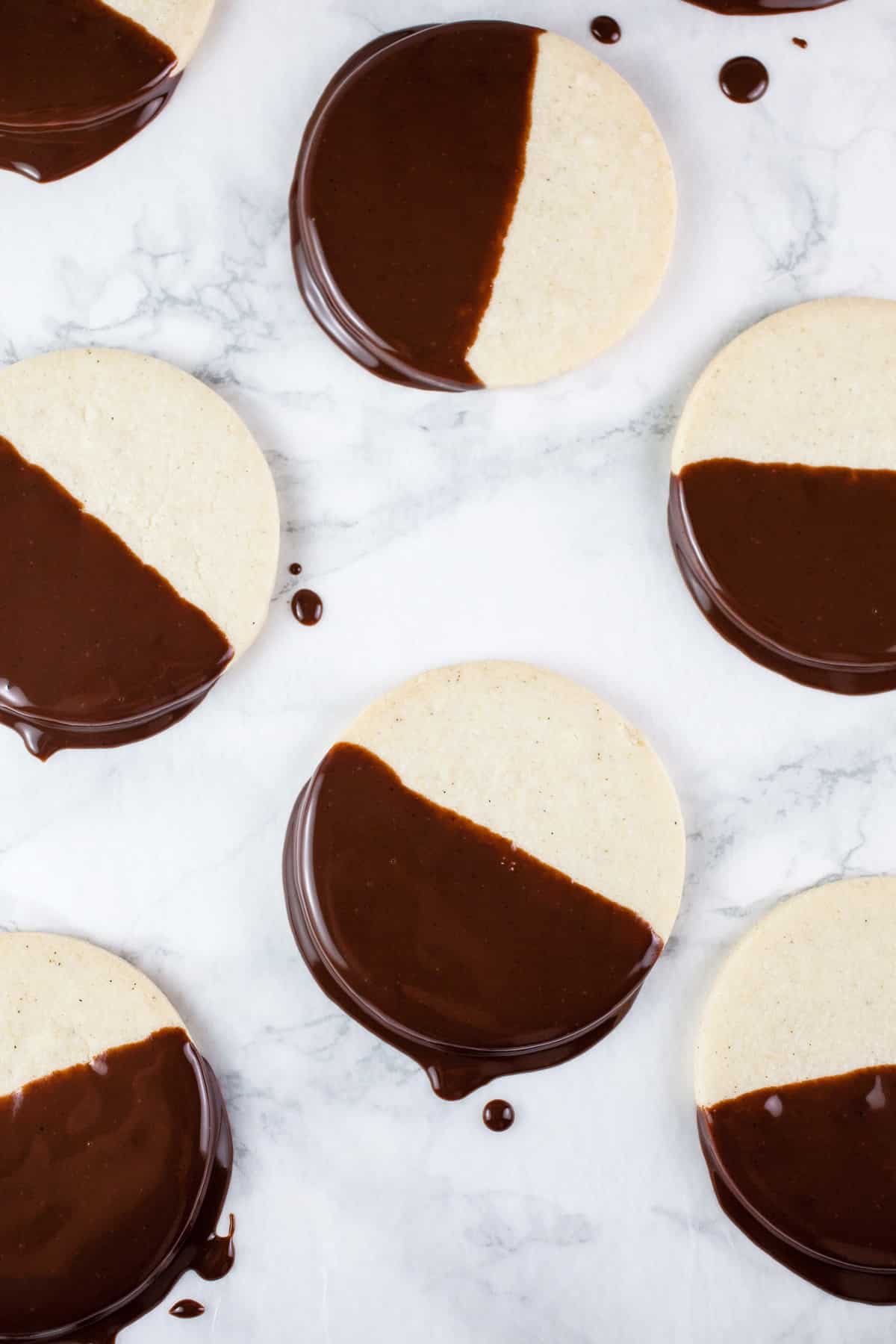 Shortbread cookies dipped in chocolate ganache on white surface.
