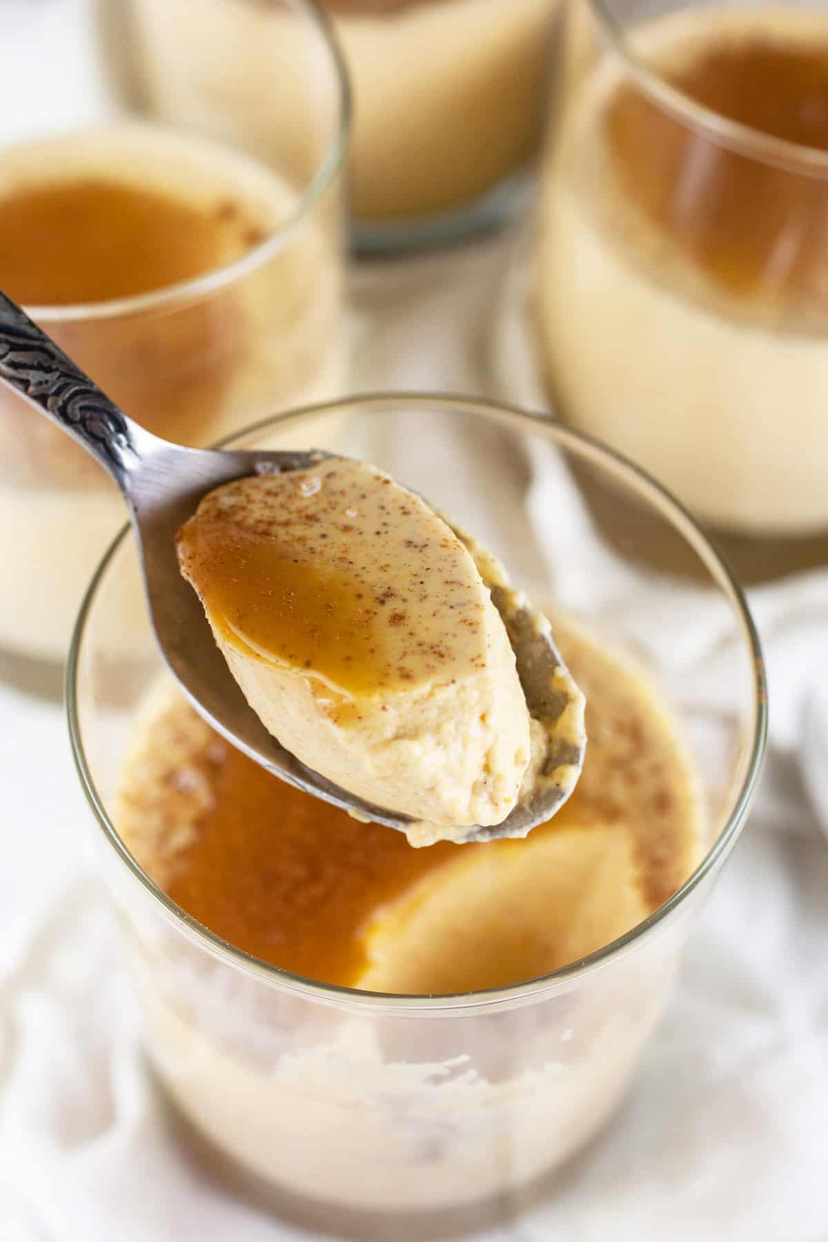 Spoonful of pumpkin panna cotta with caramel sauce lifted from glass.