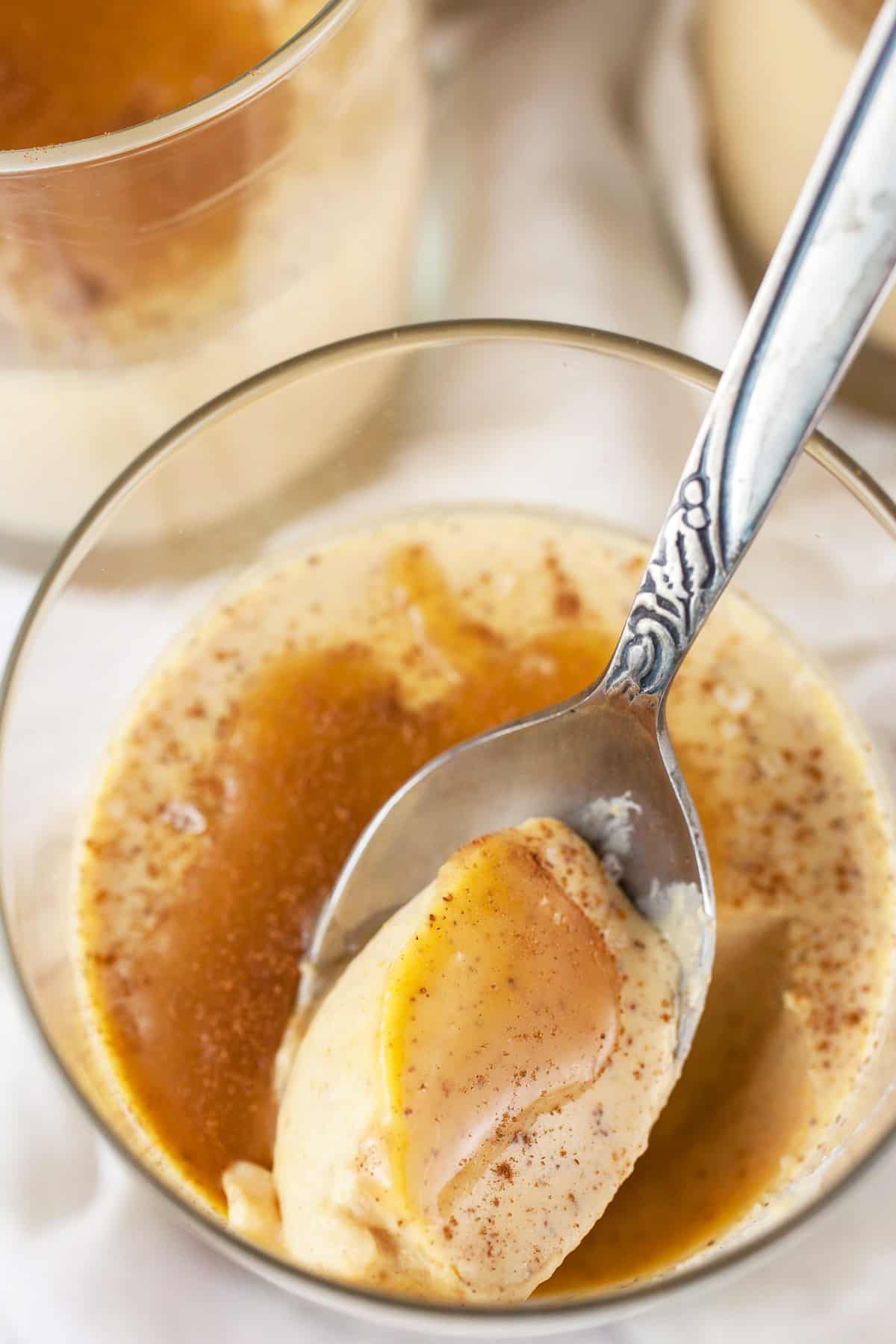 Pumpkin panna cotta with caramel sauce in glass with spoon.