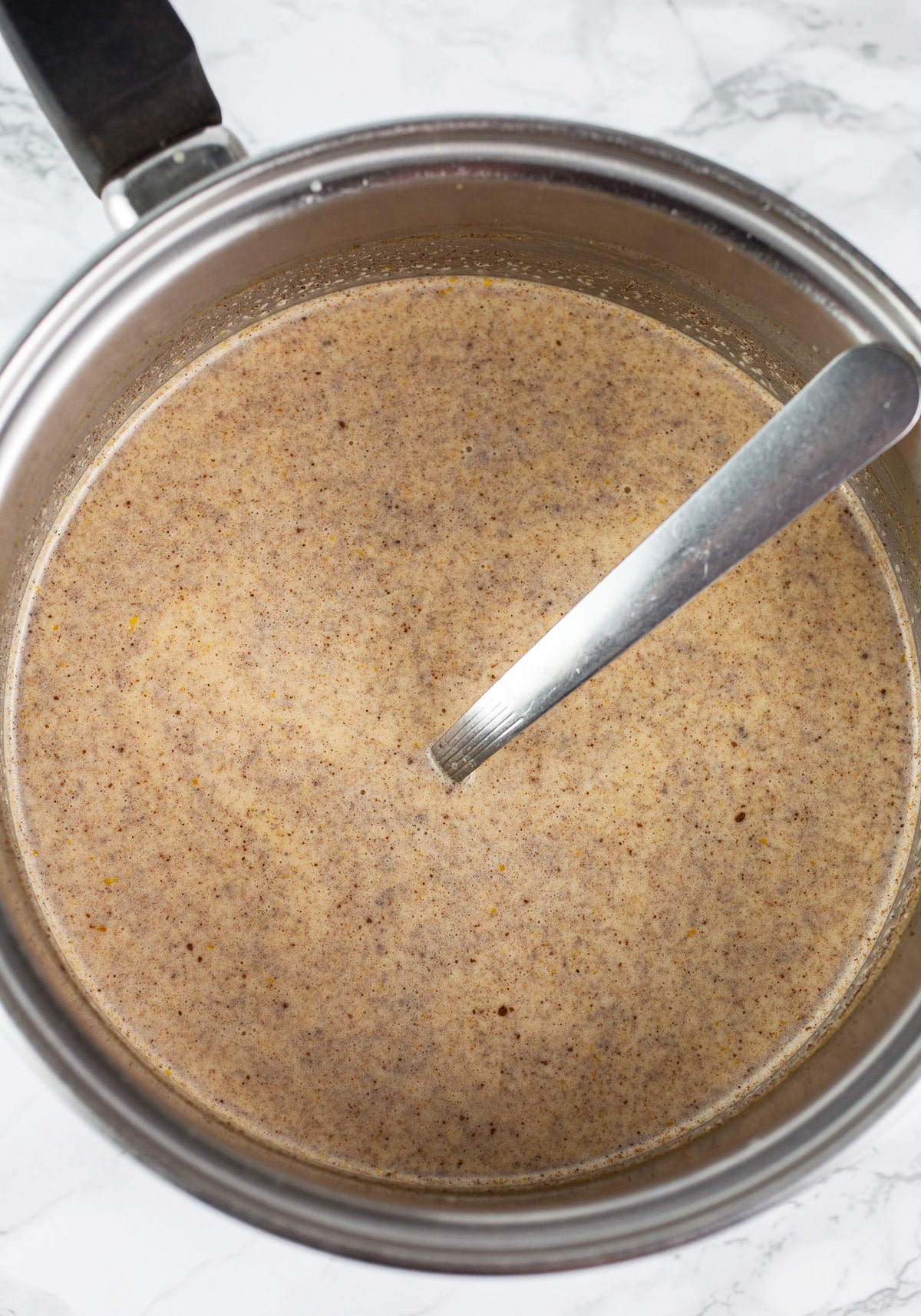 Heavy cream mixture with pumpkin puree and spices in sauce pan.