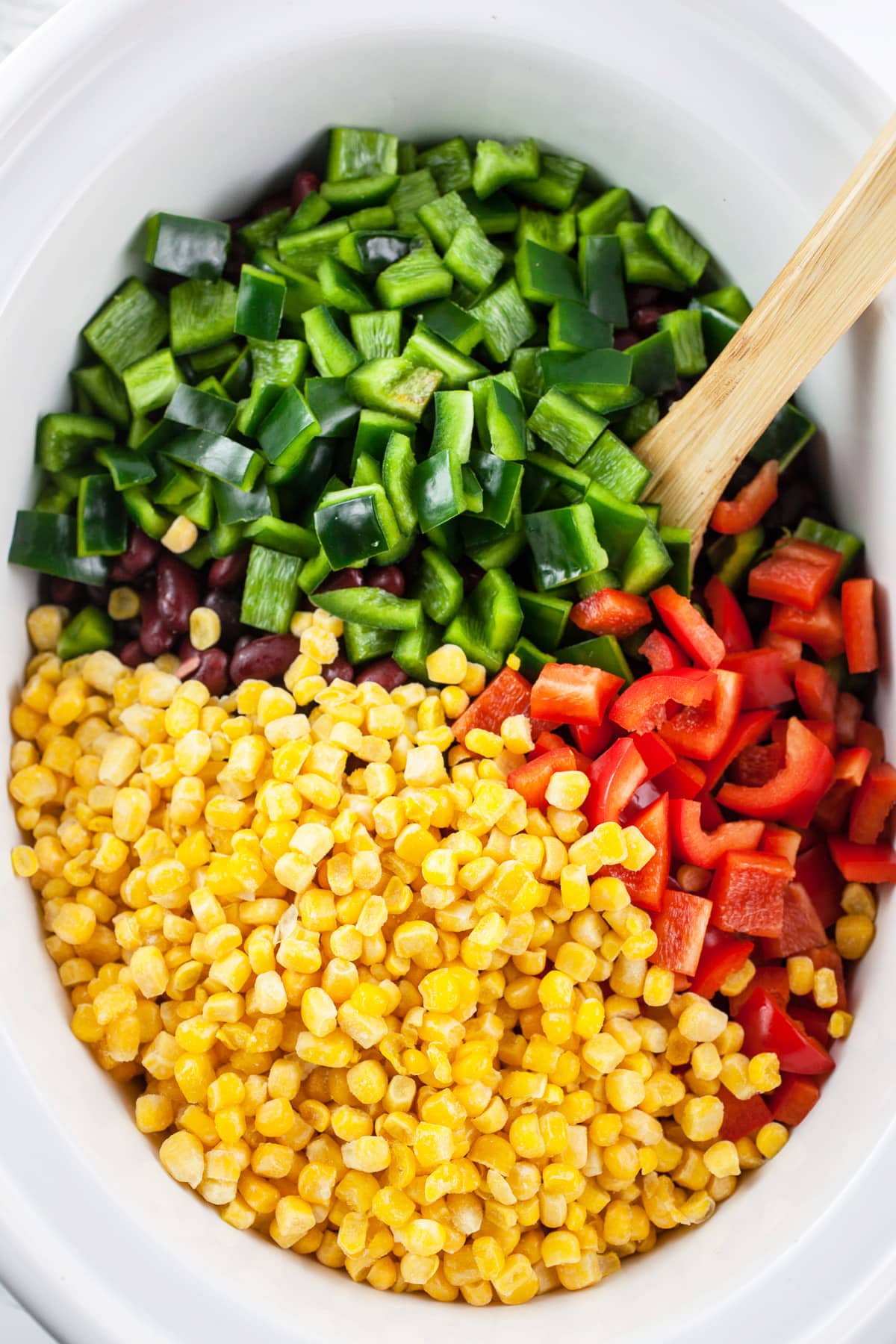 Red bell peppers, poblano peppers, and corn in slow cooker.