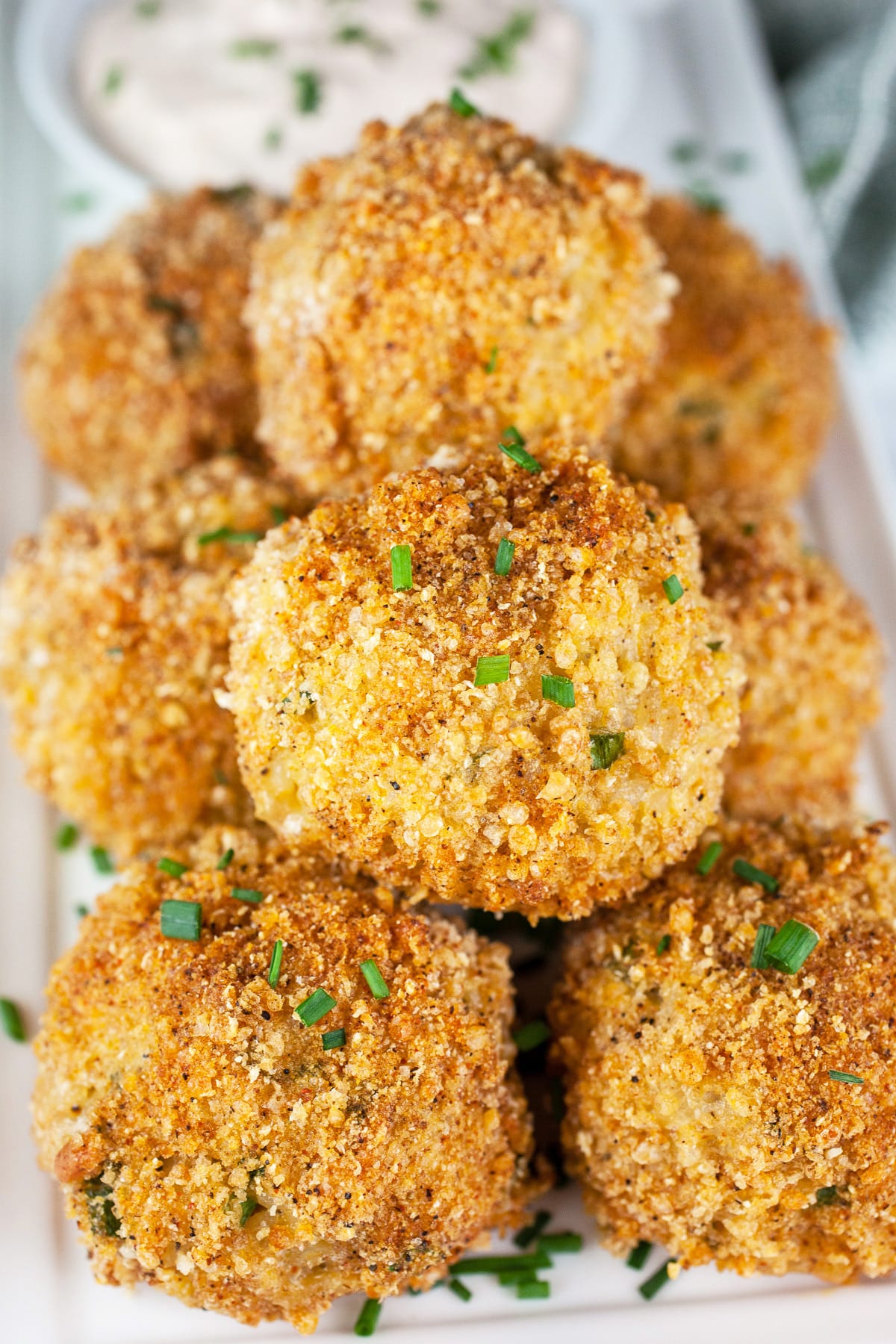 Baked rice balls on white platter with chipotle sour cream.