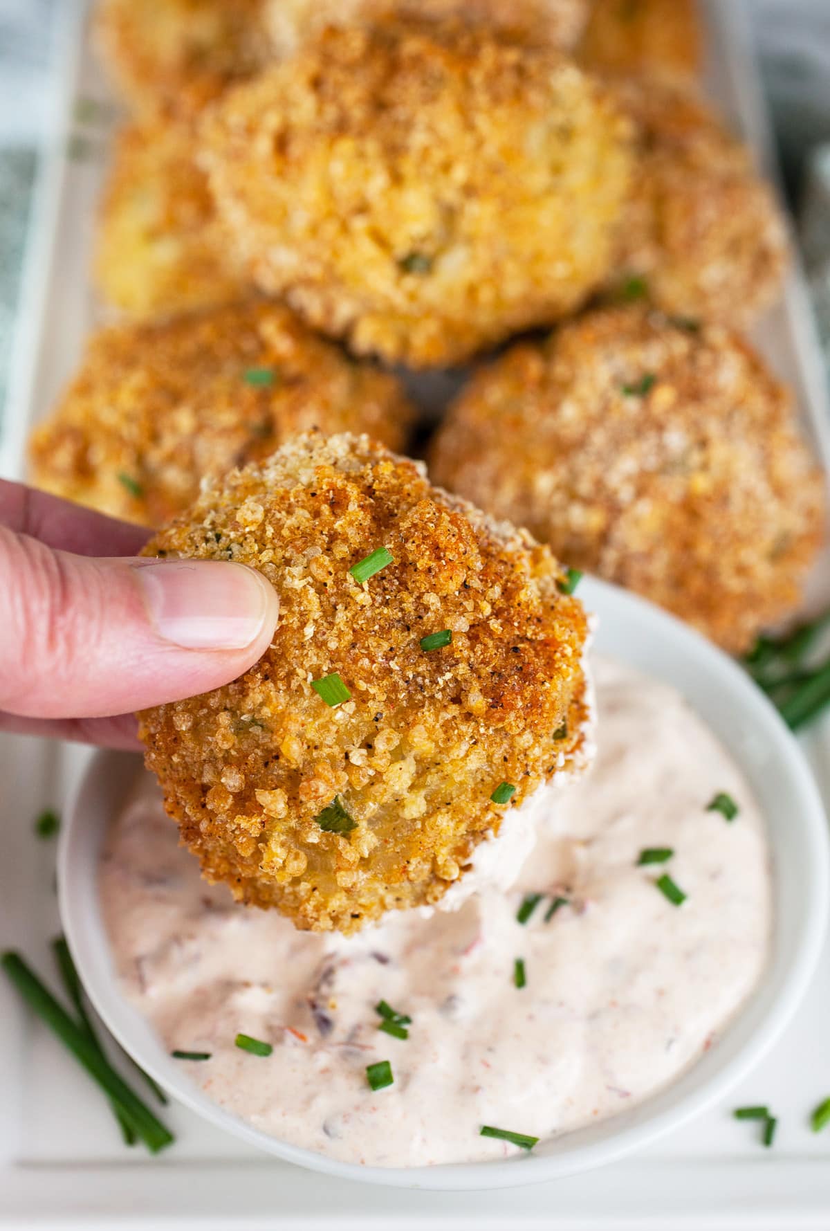 #ad These Cheesy Rice Balls with Chipotle Dipping Sauce are the perfect appetizers for your next party! The Italian arancini recipe gets a Mexican twist with this zesty rice ball recipe. This vegetarian rice appetizer is rolled in bread crumbs and baked. It's served with a chipotle dipping sauce made with sour cream, adobo sauce, and honey. Your guests will love this dish! @MahatmaRice #MahatmaRice #riceballs #cheesy #arancini #appetizers #chipotle Baked rice balls dipped into chipotle sour cream.