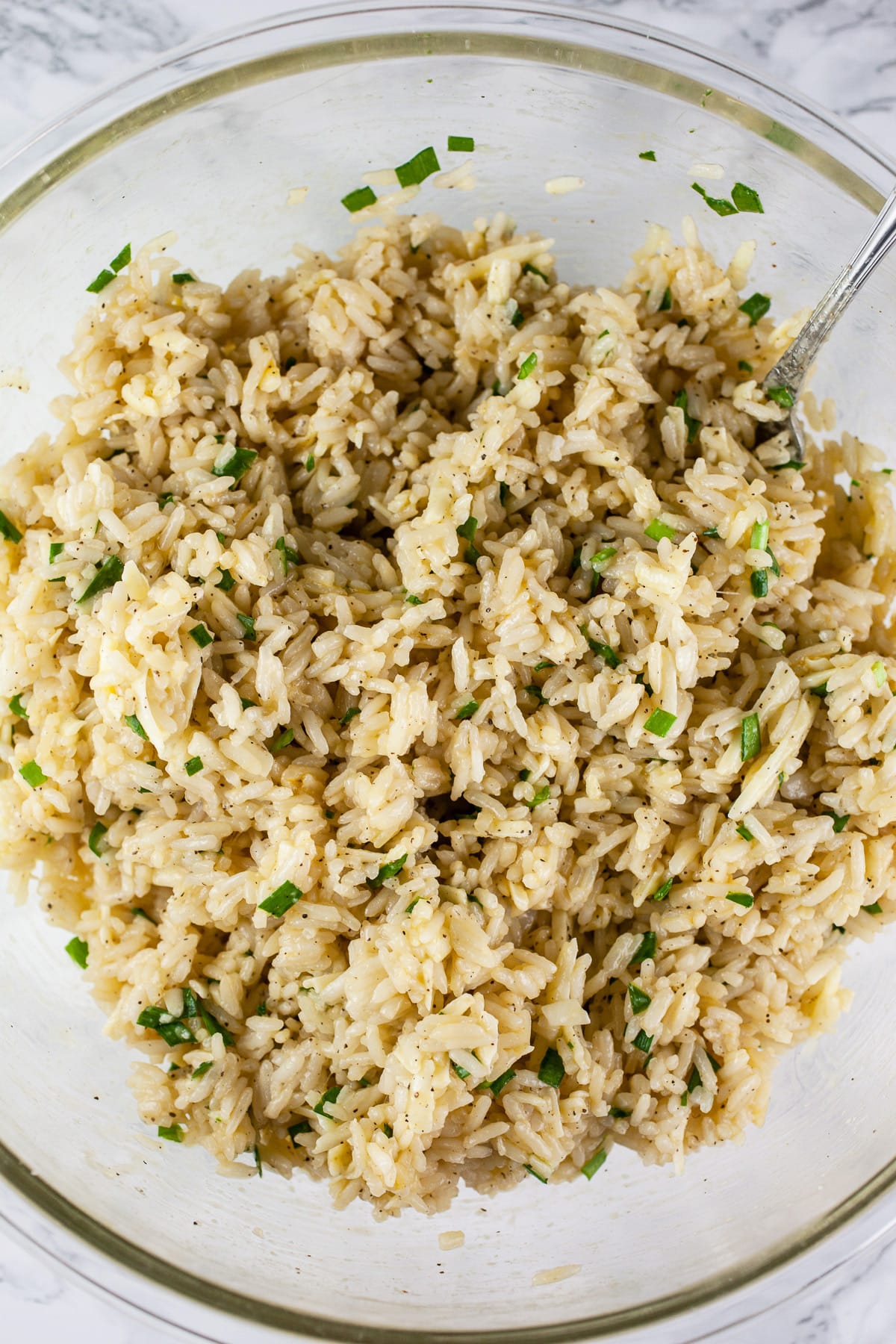 Rice, egg, cheese, and herb mixture in glass mixing bowl.