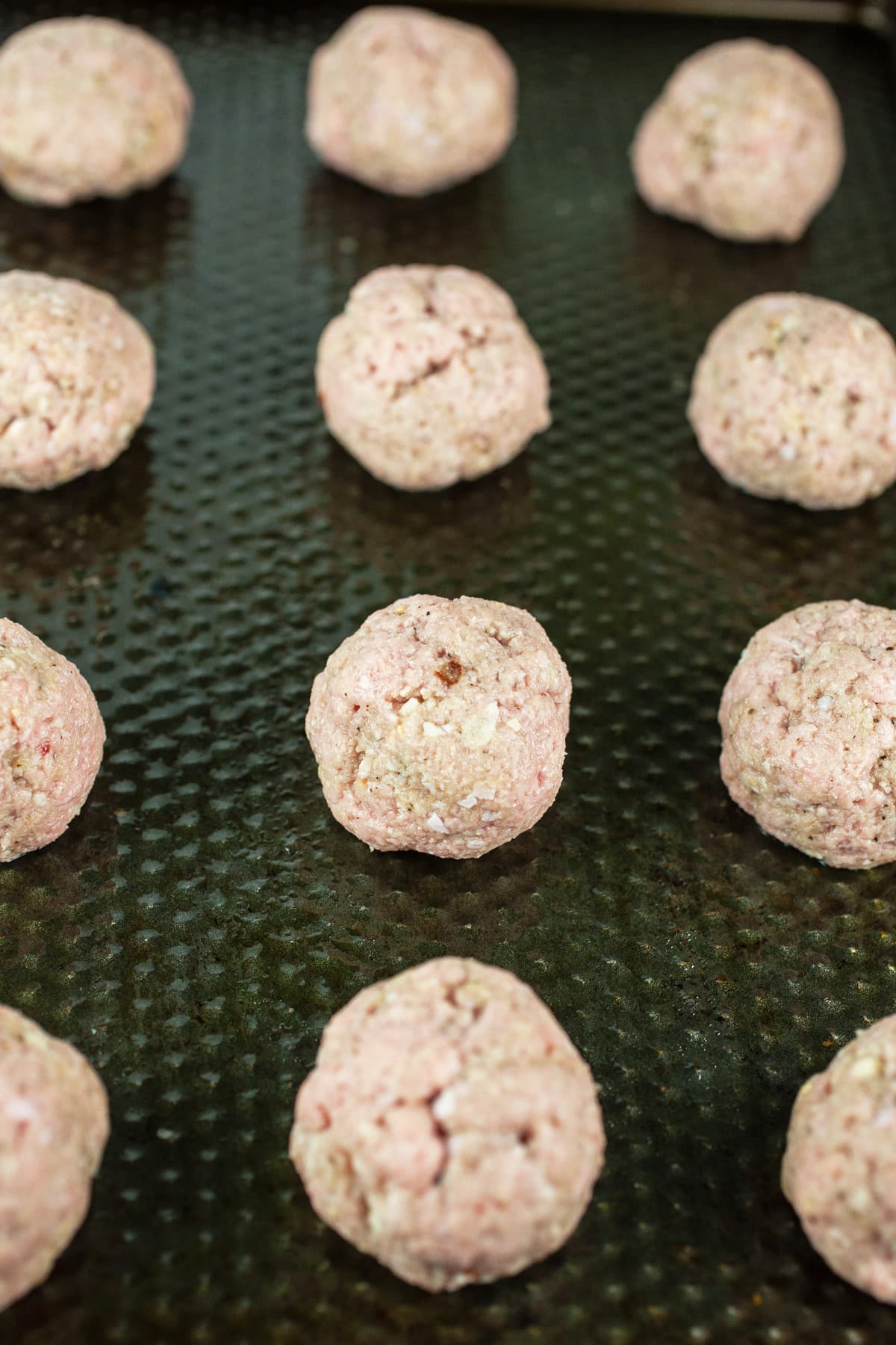 Uncooked turkey meatballs on baking sheet.