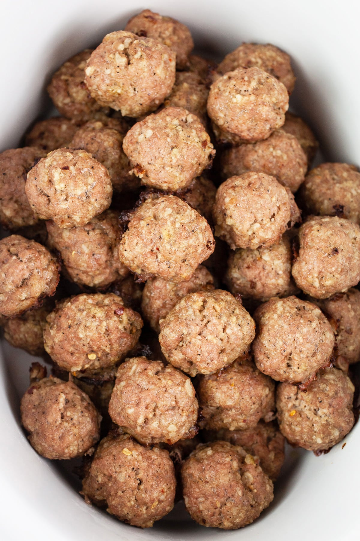 These Crockpot Teriyaki Meatballs are easy to make and full of flavor! These Asian meatballs are made with turkey, baked in the oven, and covered with a sticky sweet and savory sauce. They're warmed in the slow cooker so they're great for holiday parties like Christmas and New Year's Eve. Also great for Game Day. They're gluten free as well! #crockpot #meatballs #turkey #teriyaki #glutenfree Baked meatballs in slow cooker.