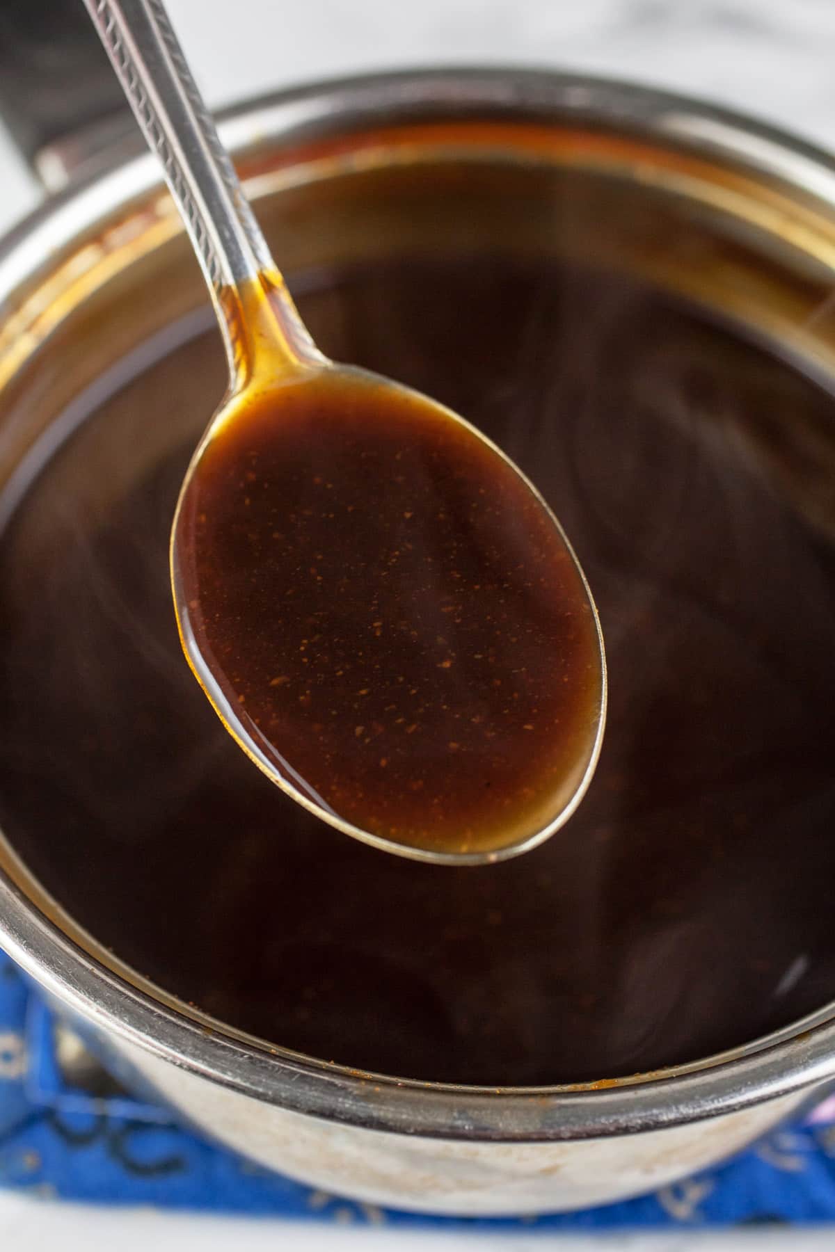 Spoonful of teriyaki sauce lifted from sauce pan.