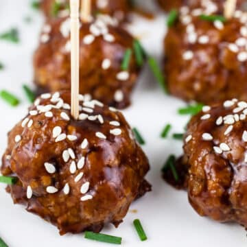 Teriyaki turkey meatballs on white platter with toothpicks.