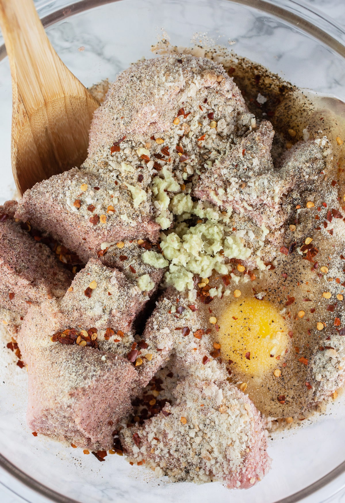 Raw ground turkey meatball ingredients in large glass mixing bowl.