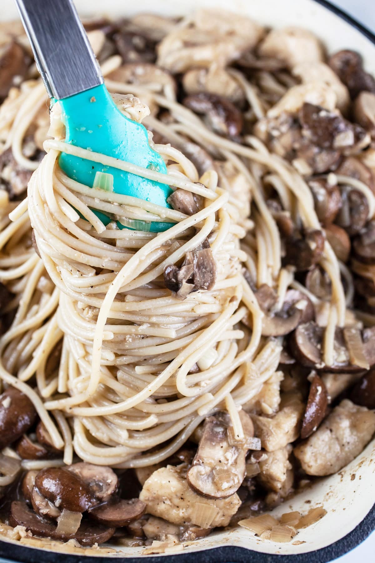 This Easy Chicken Marsala Pasta Recipe is one of the best Italian comfort foods out there! Chicken marsala is a classic Italian dish made with lots of mushrooms and marsala wine. I love to toss it with pasta noodles and a lightly creamy sauce. This version is a bit healthier than the traditional version. I love to make an authentic pasta at home. It's more fun than going out to any restaurants. Here's to Italian meals! #chicken #marsala #pasta #easy #Italian #mushrooms #dinner #recipes Chicken marsala pasta lifted from skillet using tongs.