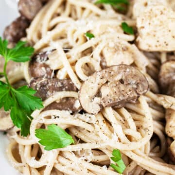 Chicken marsala pasta with fresh parsley in white bowl.