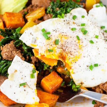 Sweet potato turkey hash with over easy egg cut with fork.