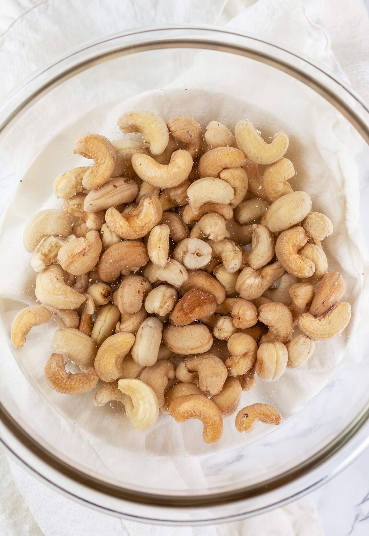 Cashews soaking in water in glass bowl.