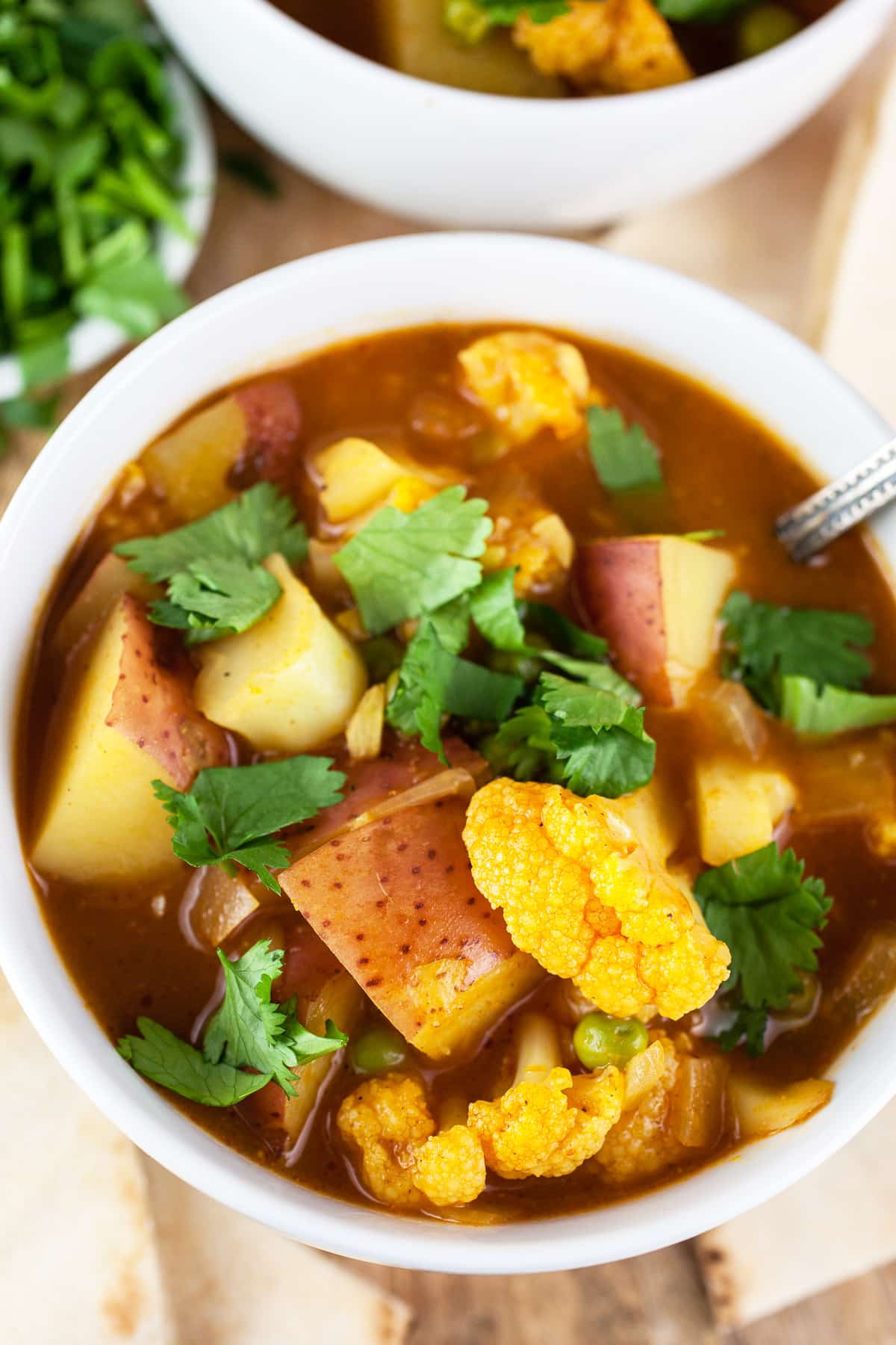 Curried cauliflower potato soup in white bowls with pita bread.