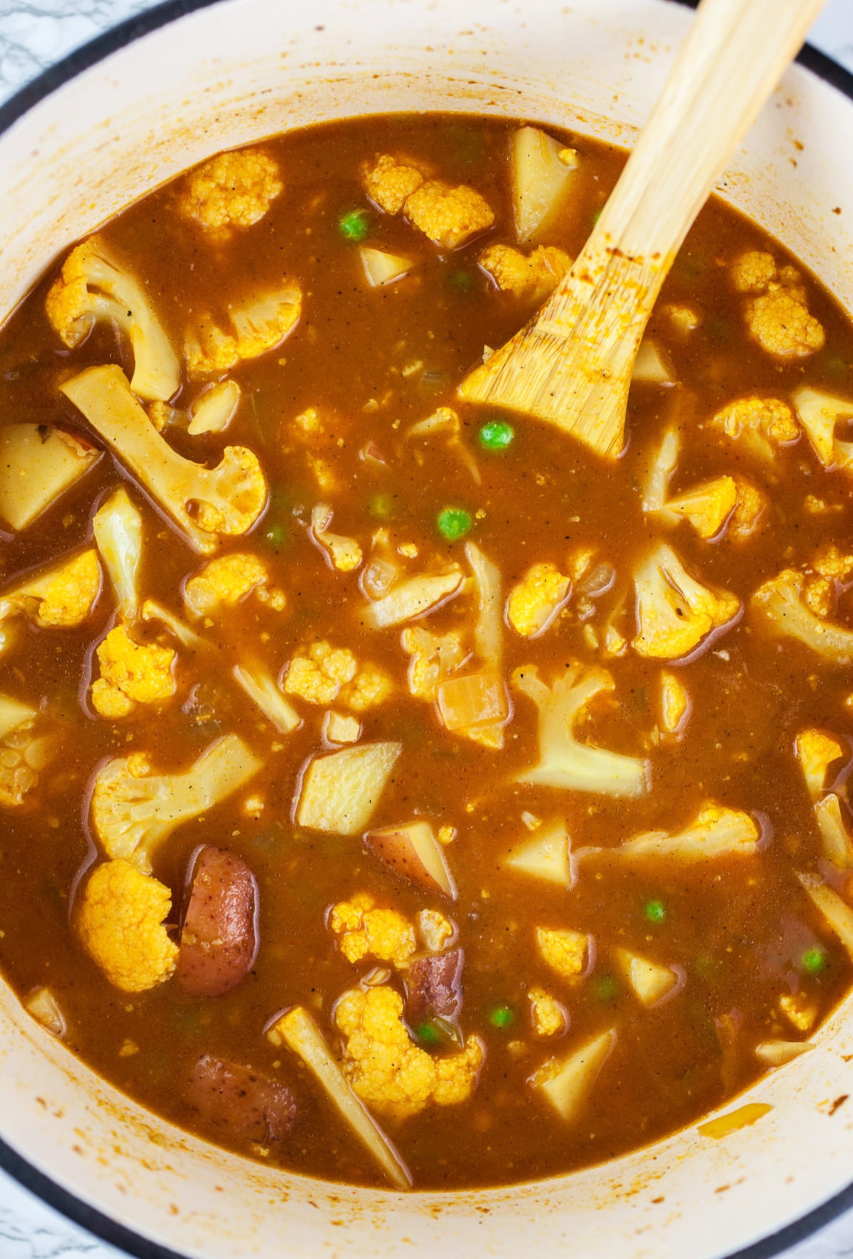 Cauliflower and potatoes simmered in tomato broth in Dutch oven.