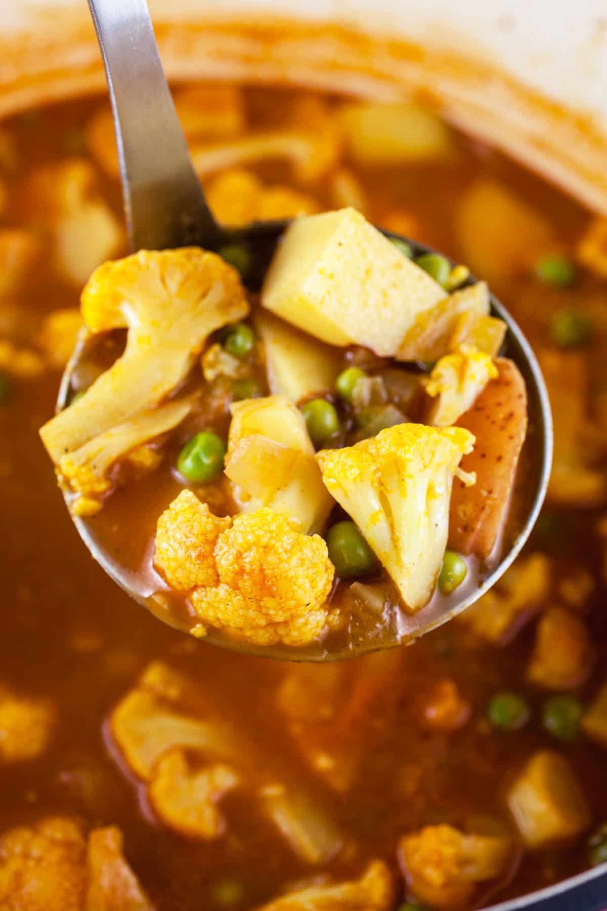 Scoop of curry cauliflower potato soup lifted from Dutch oven.