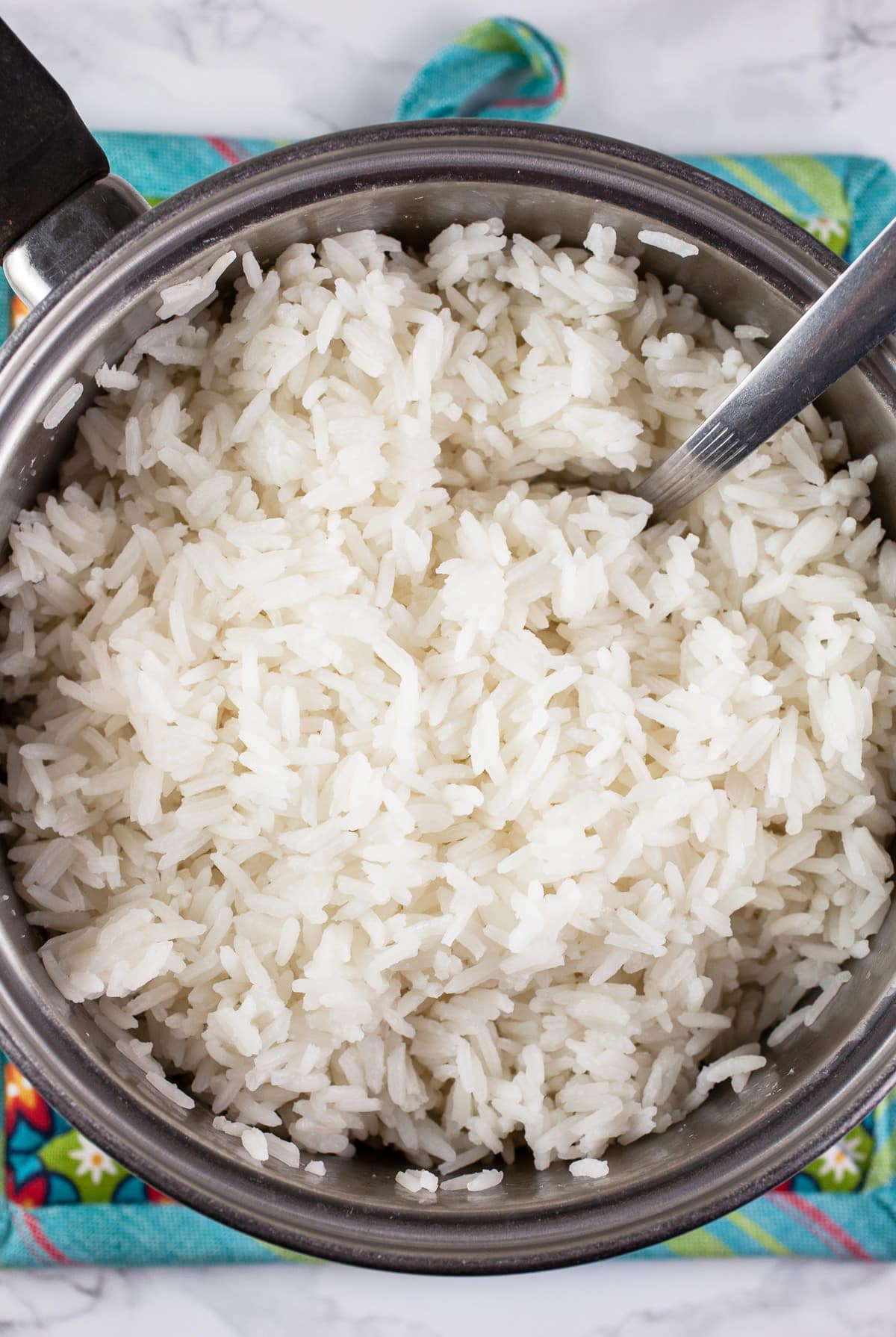 Cooked rice in small pot with spoon.