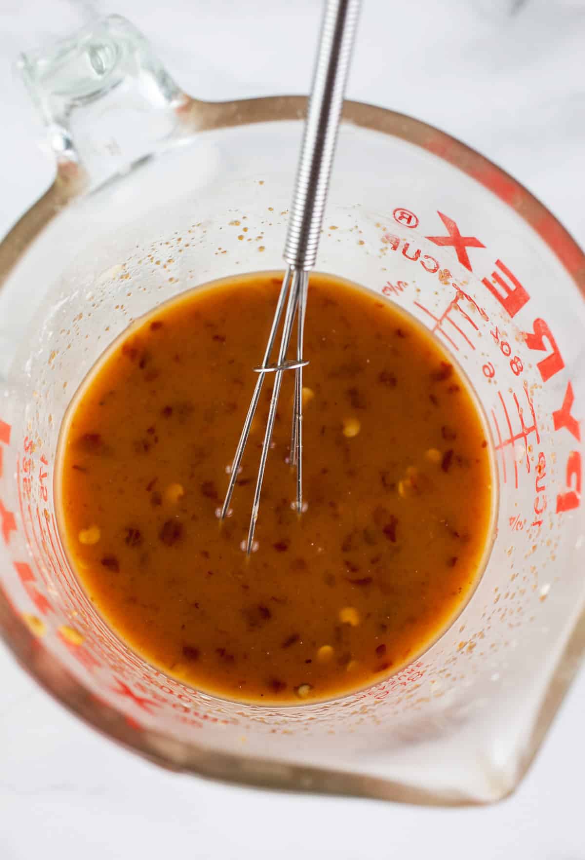 Korean sauce in glass measuring cup with small whisk.