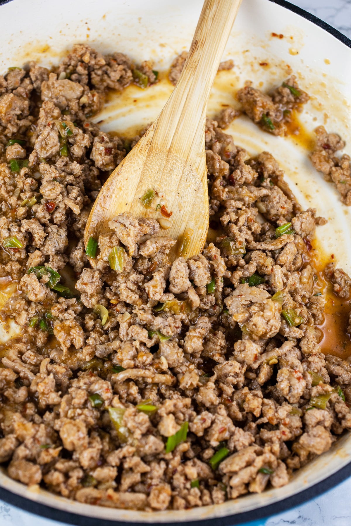 Cooked ground turkey with Korean sauce in skillet with wooden spoon.