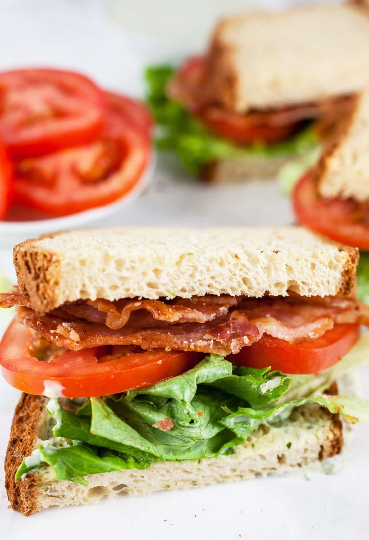 BLT sandwiches cut into halves with tomatoes.