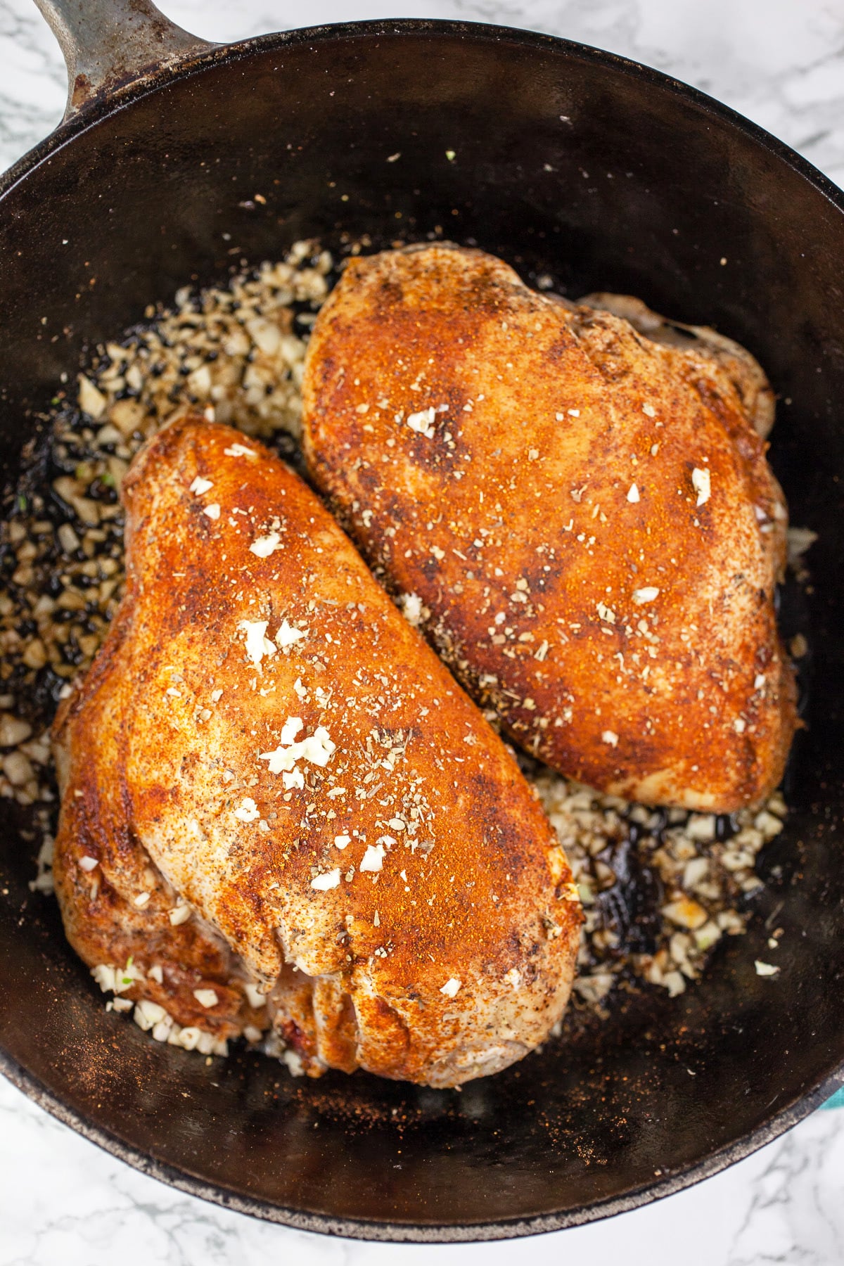 Split chicken breasts with garlic and spices sautéed in cast iron Dutch oven.