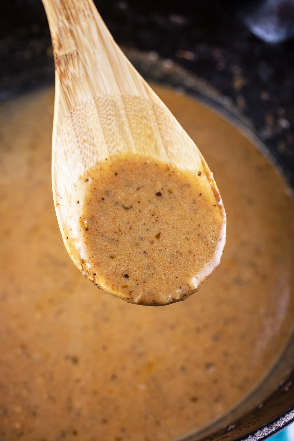Pan sauce lifted from Dutch oven on wooden spoon.