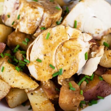 Dutch oven chicken and potatoes with sauce and minced chives.