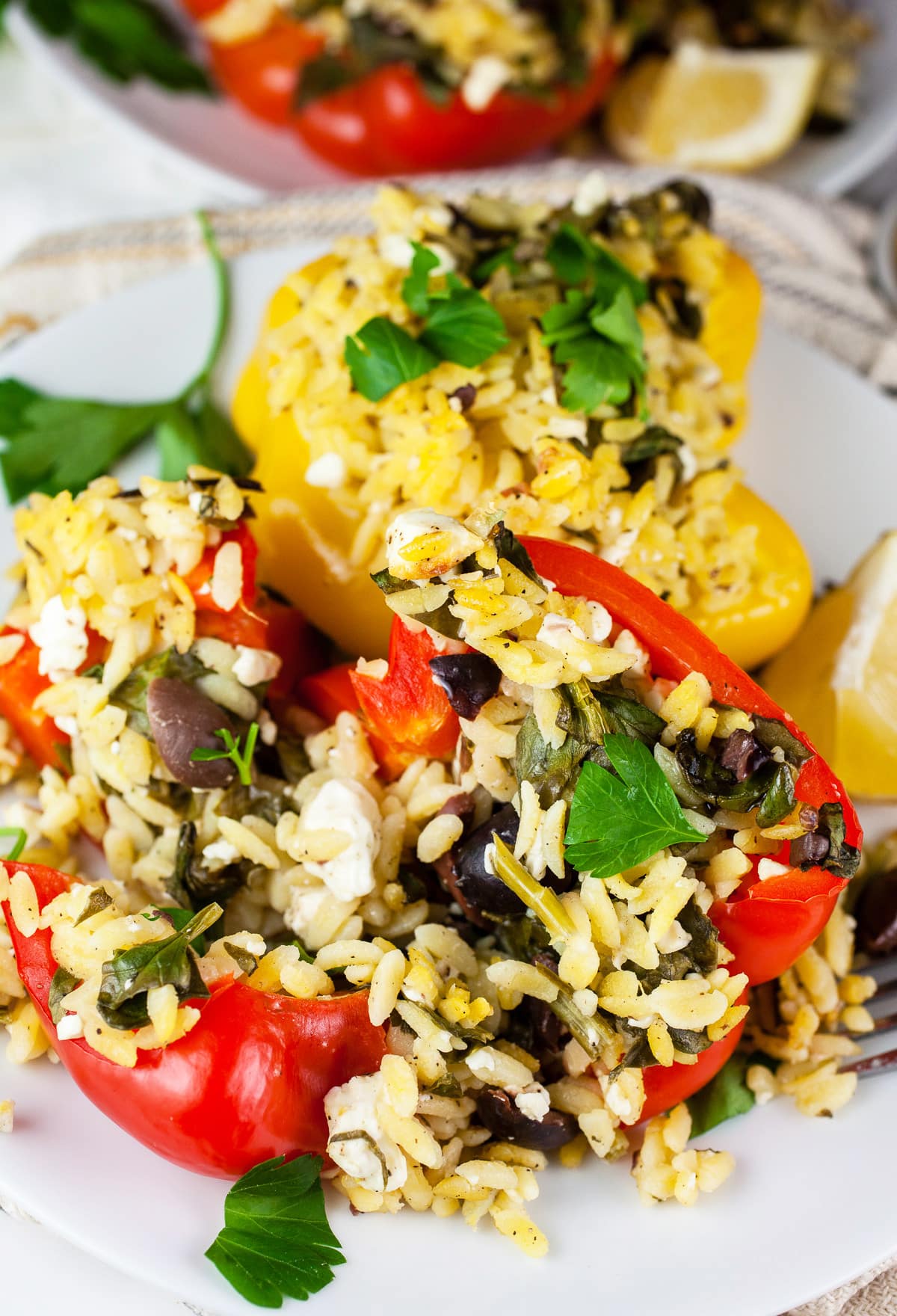 Greek orzo stuffed peppers with parsley and lemon wedges.