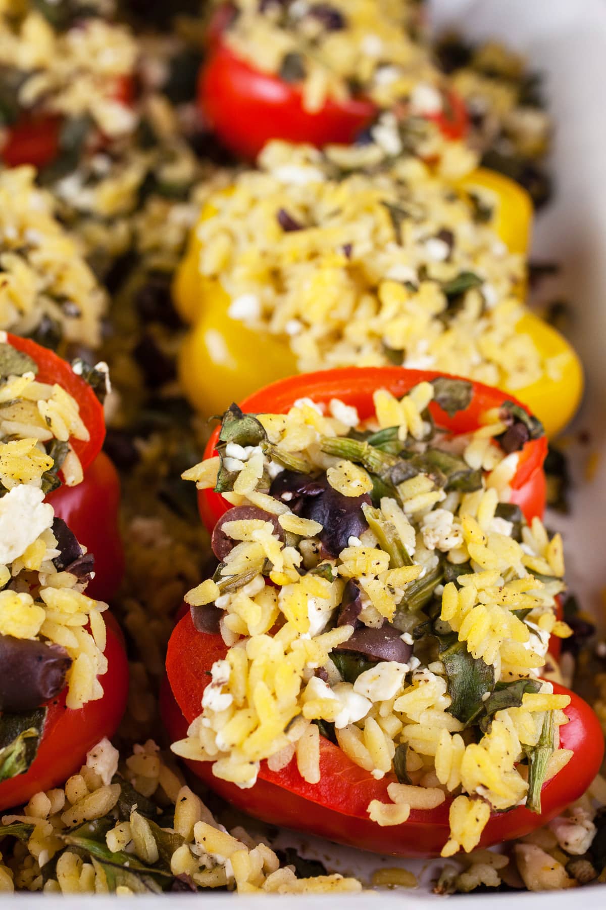 Cooked Greek stuffed peppers in ceramic baking dish.