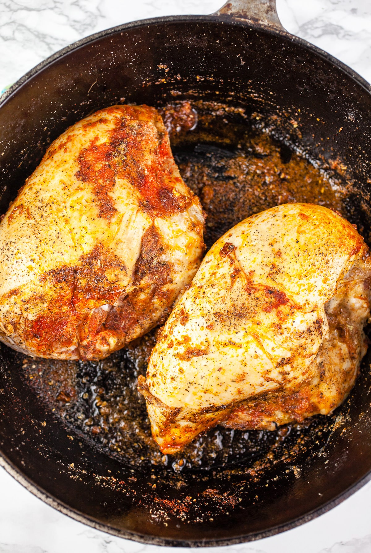 Split chicken breasts sautéed with spices in Dutch oven.