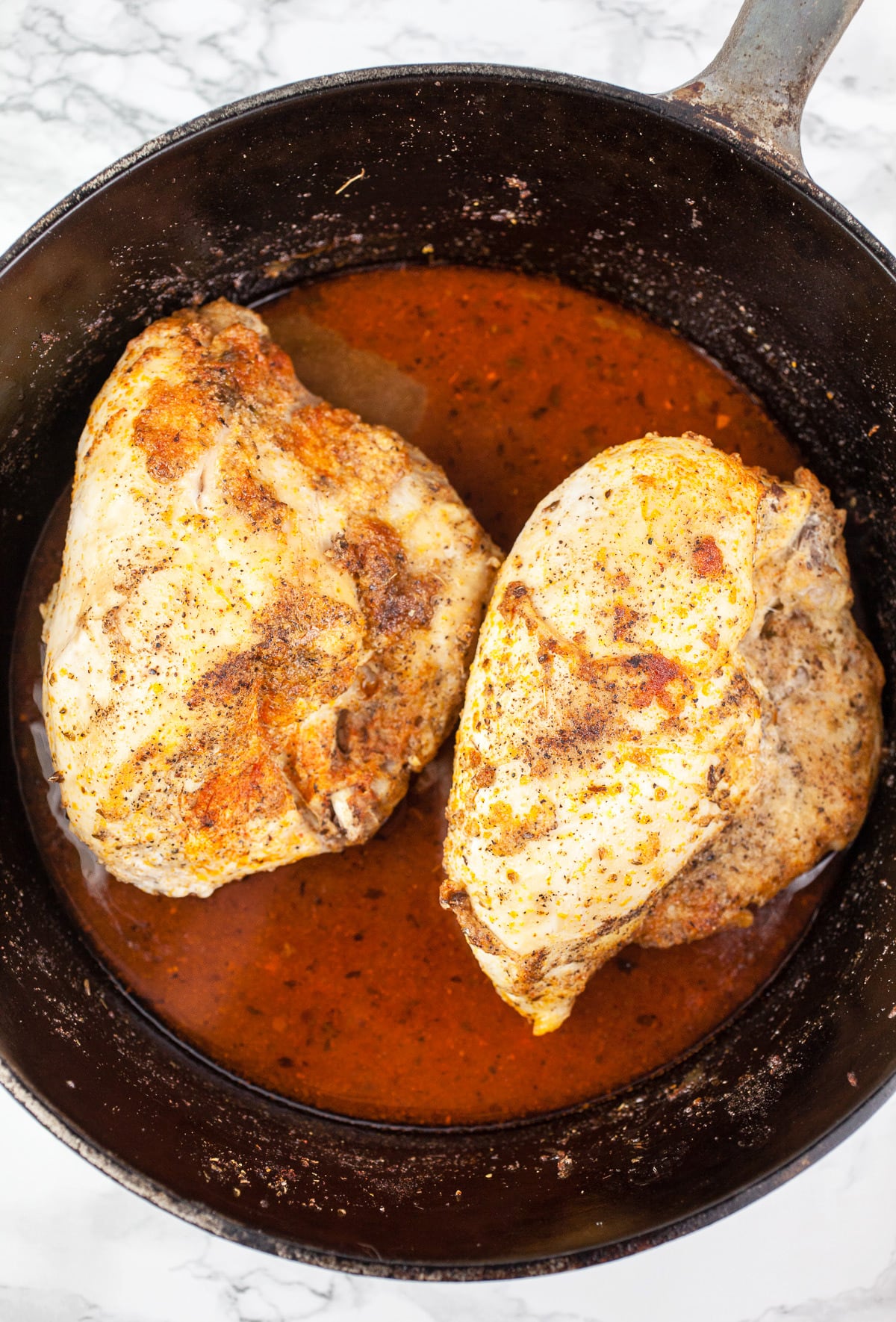 Cooked split chicken breasts and broth in Dutch oven.