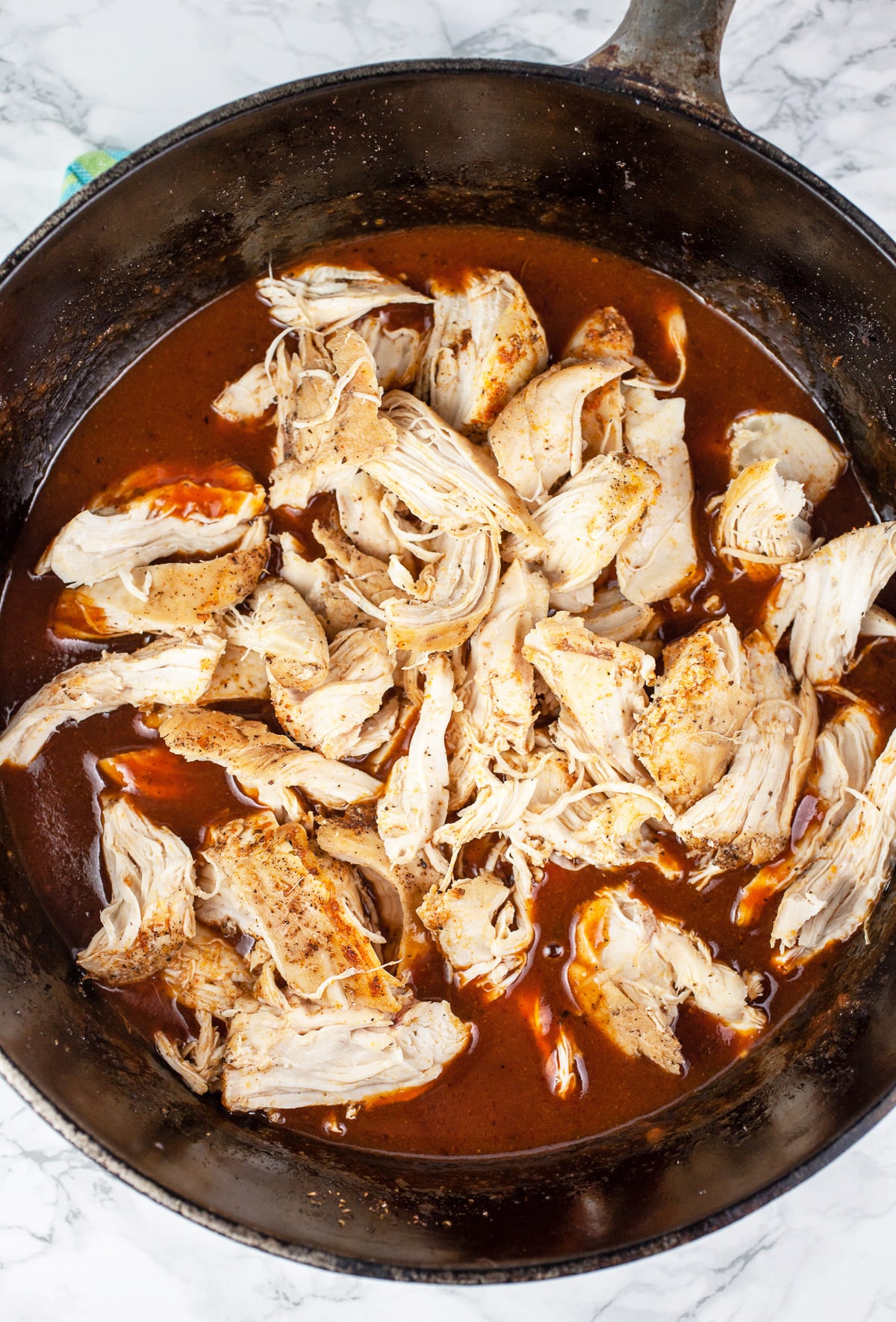Shredded chicken and BBQ sauce in Dutch oven.