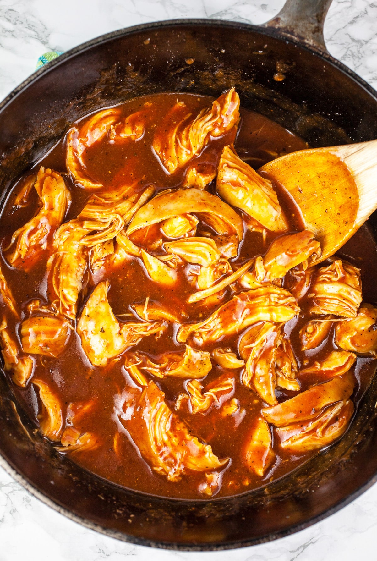 Pulled chicken tossed in BBQ sauce in Dutch oven.