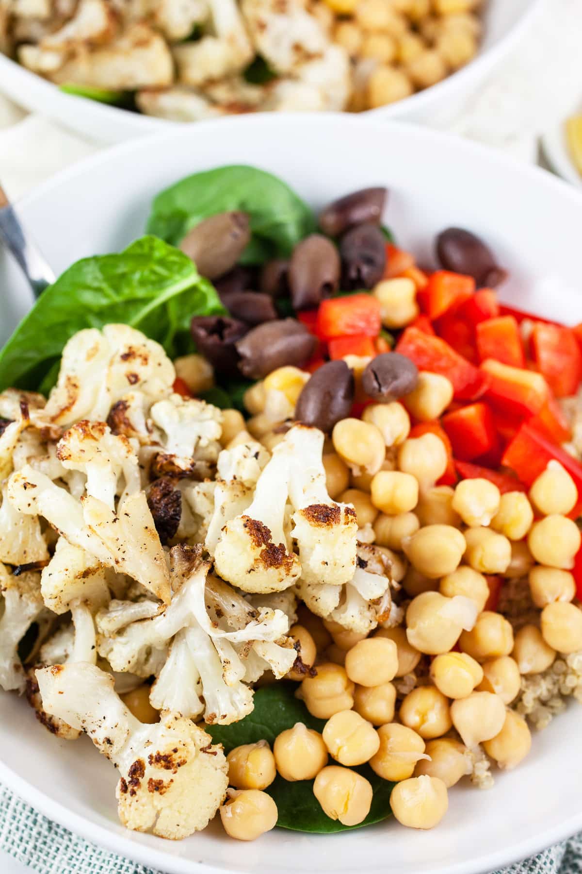 Mediterranean chickpea bowls with cauliflower, red bell pepper, Kalamata olives, and spinach.