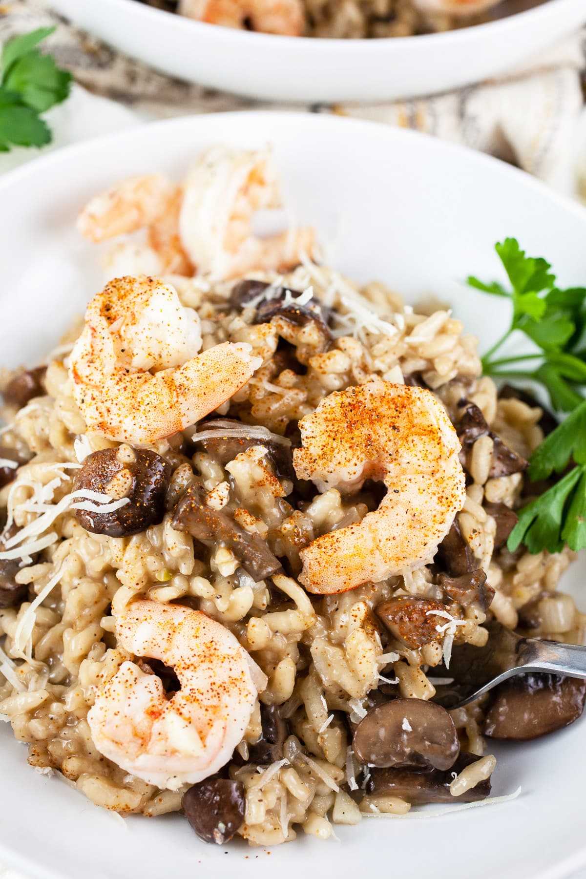 Mushroom shrimp risotto with parsley in white bowls.