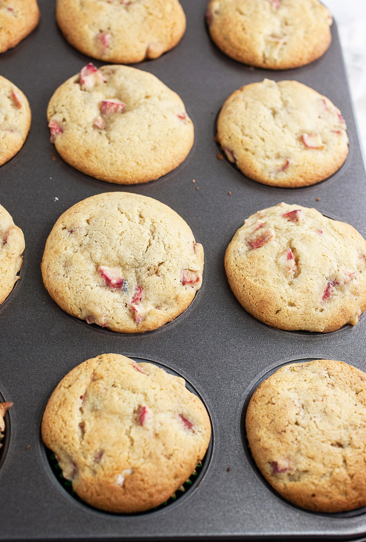 Baked rhubarb muffins in metal muffin tin.