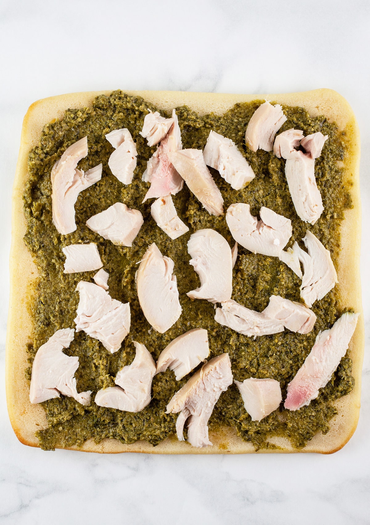 Basil pesto and shredded chicken on flatbread.