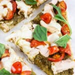 Chicken pesto flatbread with fresh basil cut into slices.