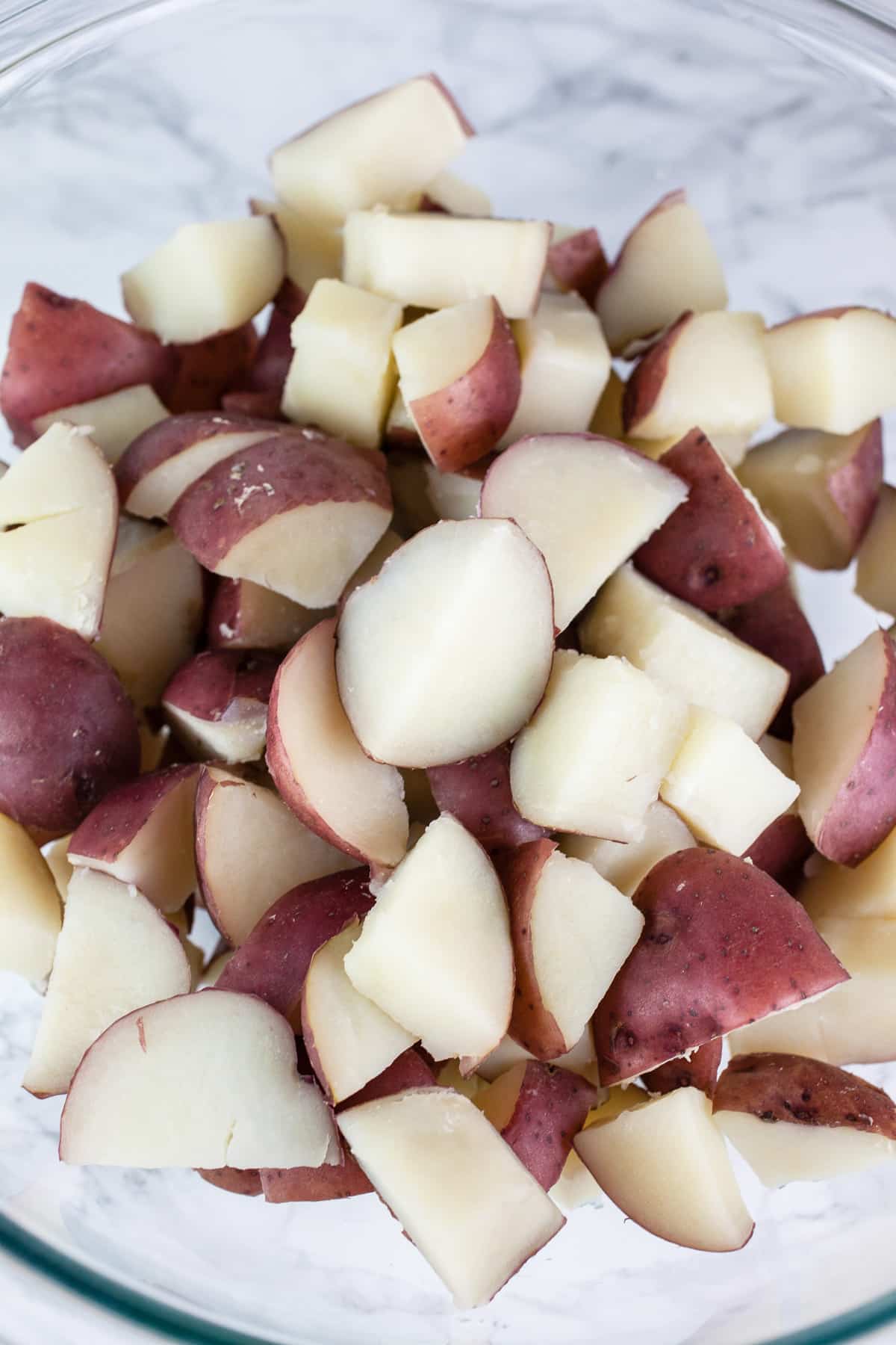 Boiled red potatoes in large glass bowl.