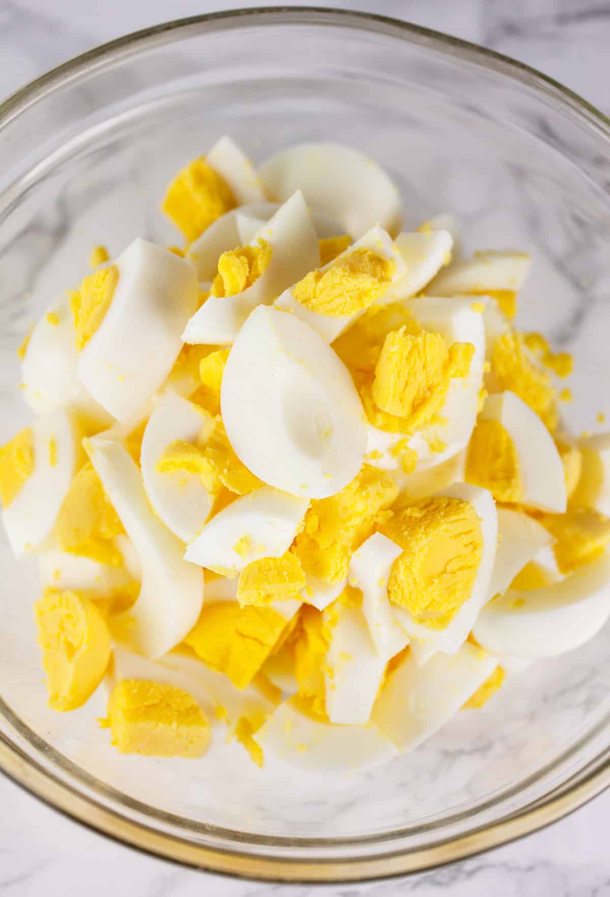 Chopped hard boiled eggs in small glass bowl.